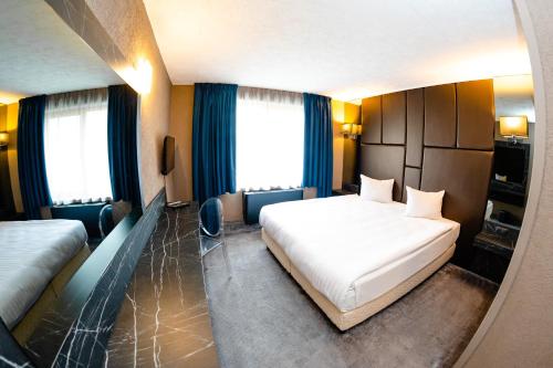 a bedroom with a large white bed and blue curtains at Hotel Ciao in Târgu-Mureş