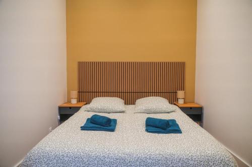 a bedroom with a bed with two blue pillows on it at Le Cocon du Golf in Nîmes