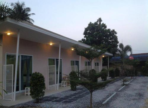 a building with white shutters and a tree in front of it at Baan Chan Suan in Nong Nam Daeng