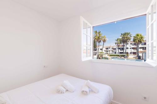 a white bed with two pillows and a window at Siesta Mar Apartamentos in Cala en Porter