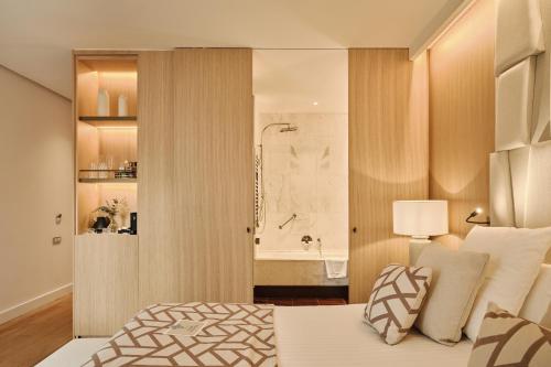 a bedroom with a bed and a bathroom with a tub at Hospes Palau de La Mar, Valencia, a Member of Design Hotels in Valencia