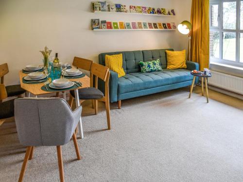 a living room with a blue couch and a table at Bittern Lodge in Cromer