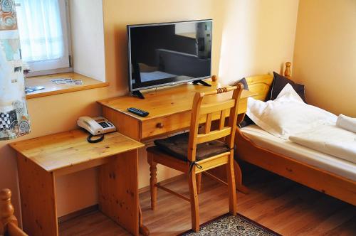 a bedroom with a desk with a television and a bed at Penzion Diana in Teplice nad Bečvou