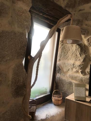 ein Fenster in einer Steinmauer mit einer Lampe in der Unterkunft Casa Media Lúa in Allariz