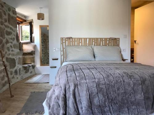 ein Schlafzimmer mit einem großen Bett und einer Steinwand in der Unterkunft Casa Media Lúa in Allariz
