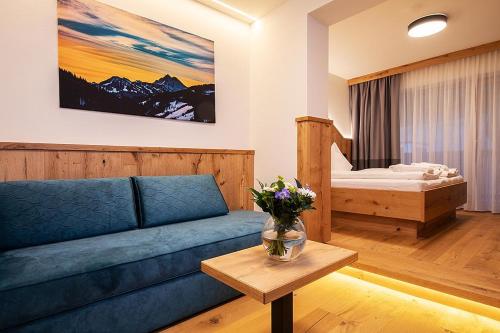 a living room with a couch and a bed at Vital Hotel Post in Dienten am Hochkönig