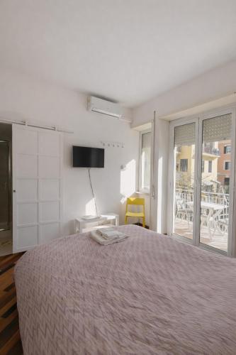 a white bedroom with a bed and a balcony at Le VELE in Lido di Ostia
