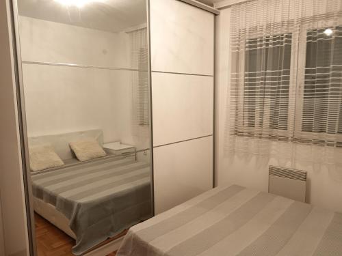 a small bedroom with a bed and a mirror at Apartman Vuk in Ćuprija