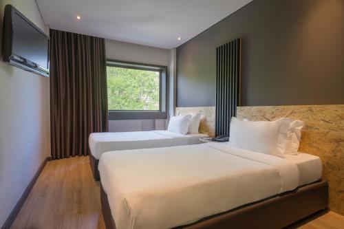 a hotel room with two beds and a television at HF Ala Sul in Porto