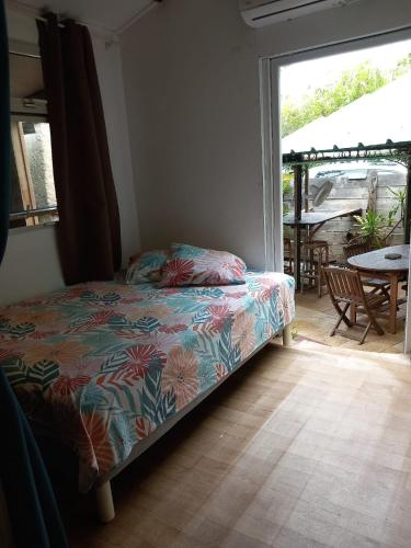 a bedroom with a bed and a patio with a table at Saline les bains petite maison bien aménagée calme & plage à pied in La Saline les Bains