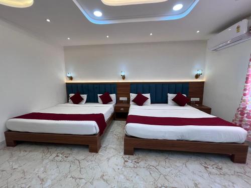 a bedroom with two beds with red pillows at Hotel Ashok Palace in Agra