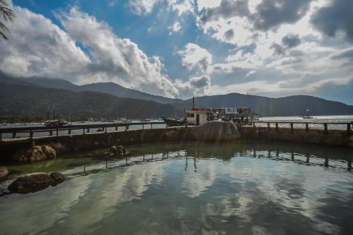 a body of water with a bridge and mountains at Aquario Pousada Hostel - Night Club in Abraão