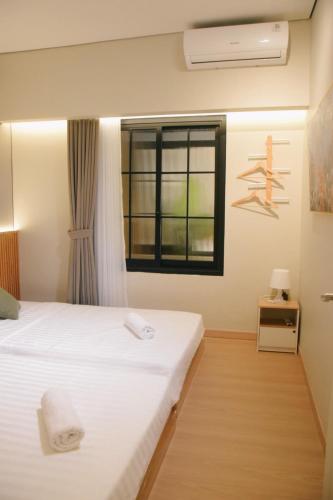 a bedroom with a white bed and a window at Liorasuite 4 Bedroom Jacuzzi Billiard Pingpong in KBP in Padalarang