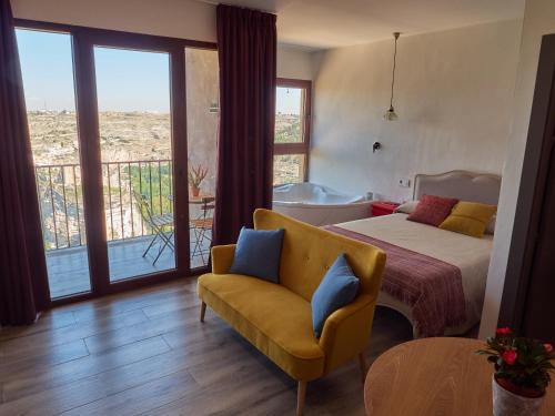 a bedroom with a bed and a chair and a balcony at Casas Rurales Maribel - Complejo Moradas del Cerro 1 - Suites con Jacuzzi en Alcalá del Júcar in Casas del Cerro