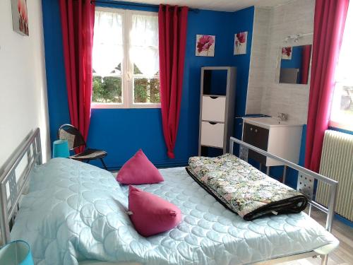 um quarto azul com uma cama com almofadas cor-de-rosa em Les Gites de Castera em Aire-sur-lʼAdour