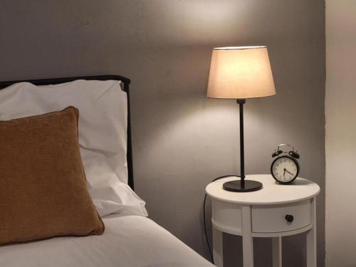 a bed with a lamp and a clock on a side table at Urban Jungle in Brno