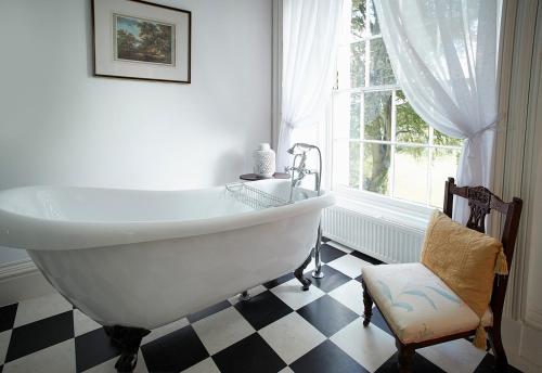 a bathroom with a tub and a chair and a window at Broomfield House in Glasbury