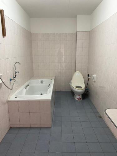 a bathroom with a bath tub and a toilet at Only fan guesthouse in Chumphon