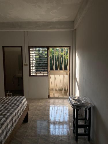 a bedroom with a bed and a table and a window at Only fan guesthouse in Chumphon