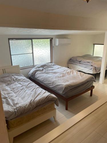 two twin beds in a room with two windows at HANARE onomichi in Onomichi