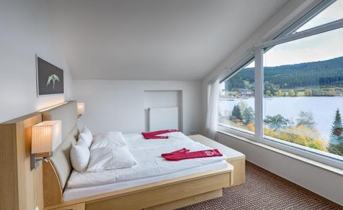a bedroom with a bed and a large window at BRUGGER' S Hotelpark Am Titisee in Titisee-Neustadt