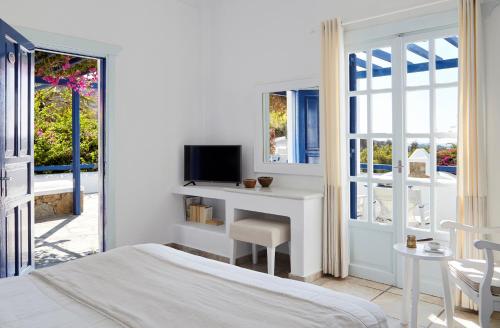 a bedroom with a bed and a desk with a tv at San Marco Hotel and Villas in Houlakia