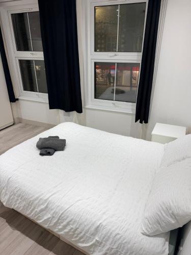 a white bed in a room with two windows at Modern Studios Elephant and Castle in London