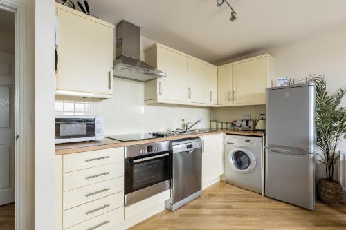 a kitchen with white cabinets and stainless steel appliances at Bay Retreat- Moments from Hamworthy Park in Poole