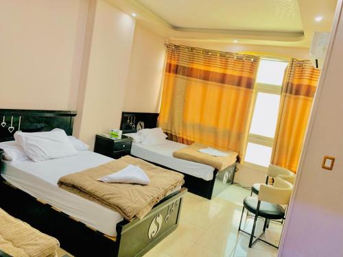 a bedroom with two beds and a chair and a window at Solitaire Plaza Hotel-Ismailia سولتير بلازا الاسماعلية in Ismailia