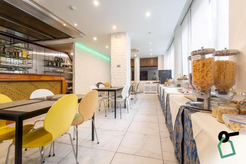 a restaurant with yellow chairs and a counter with food at Hotiday Conegliano in Conegliano