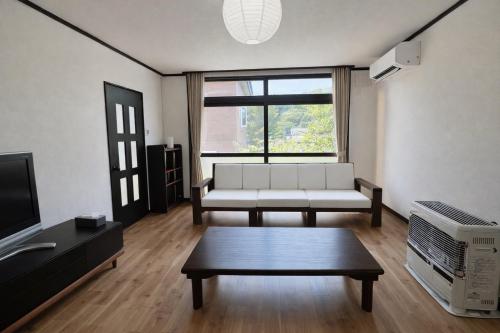 a living room with a white couch and a tv at 椴松 l フルリフォーム l 貸切の一軒家 l 千歳空港まで30分 l Todomatsu in Yuni