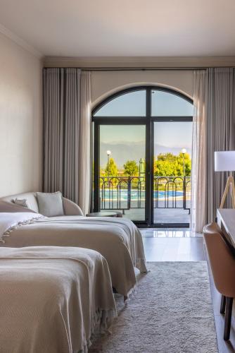 two beds in a hotel room with a large window at Panorama Kakheti Resort in Gurjaani