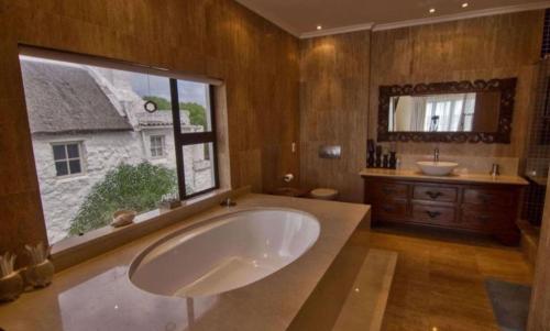 a large bathroom with a large tub and a window at Iconic Villa in Arniston in Arniston