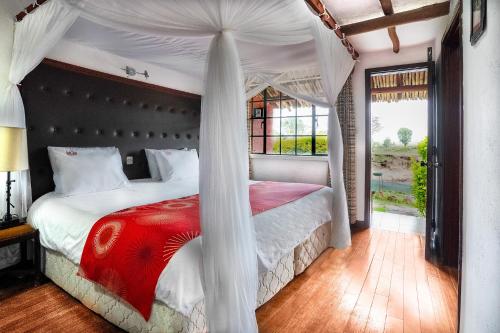 a bedroom with a canopy bed with a red blanket at Muthu Mara River Lodge in Masai Mara