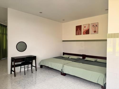 a bedroom with two beds and a table and a mirror at Nhà nghỉ Thu Hoạch in Hà Tiên