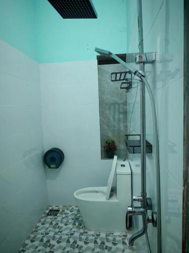a white bathroom with a toilet and a shower at Tuan Thanh Homestay in Tân Hiệp