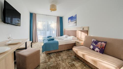 a hotel room with a bed and a couch at Welle Resort, Sun & Snow in Grzybowo