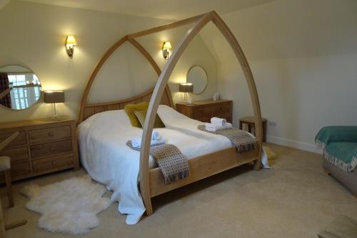 a bedroom with a canopy bed with white sheets and stuffed animals at School Room in Lochgilphead