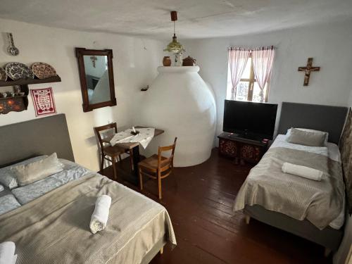 a room with two beds and a tv and a table at Kotlós Tanya in Zákányszék