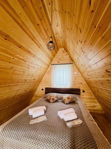 a bed in a wooden room with towels on it at Cottage Dachi in Mestia in Mestia