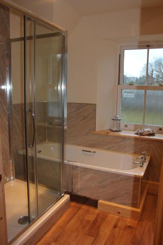 a bathroom with a shower and a tub with a window at The School House in Lochgilphead