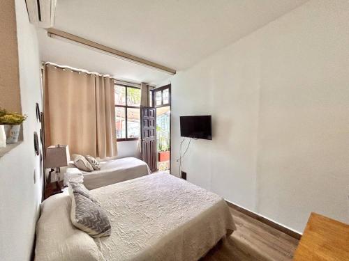 a bedroom with two beds and a tv and a window at Habitacion olas altas in Mazatlán