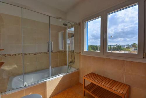 a bathroom with a tub and a bench and a window at Villa Ca Paulina in San Antonio