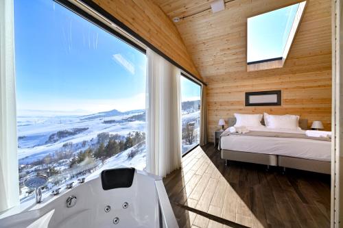 a bedroom with a bed and a tub and a window at Stonehenge Hotel & Restaurant in Tsaghkadzor