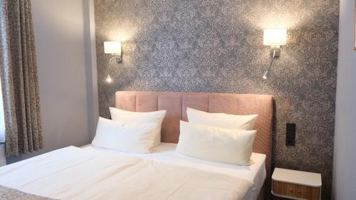 a bedroom with a white bed with white pillows at Parkhotel Flora in Bad Grund