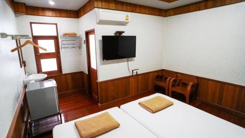 a room with a tv on the wall and a table at Baan Siriporn Resort - โรงแรมบ้านศิริพร รีสอร์ท in Samut Songkhram