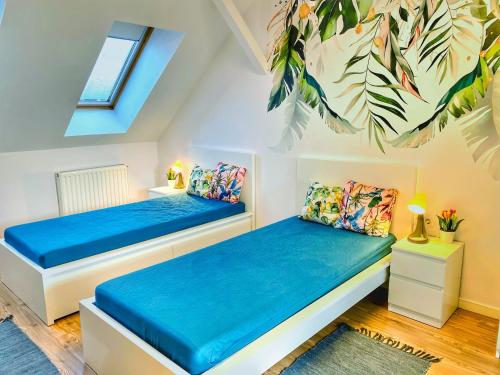 two beds in a small room with blue sheets at Magenta Apartman in Mórahalom