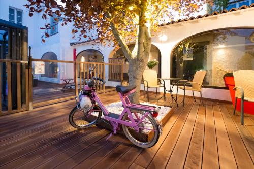 a pink bike parked on a wooden deck at Hôtel de La Marée - Face à l'océan - Ile de Ré in Rivedoux-Plage