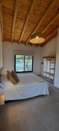 a large bed in a room with a large window at Casa de Campo Roca - Exclusivo para Parejas in Villa Cura Brochero