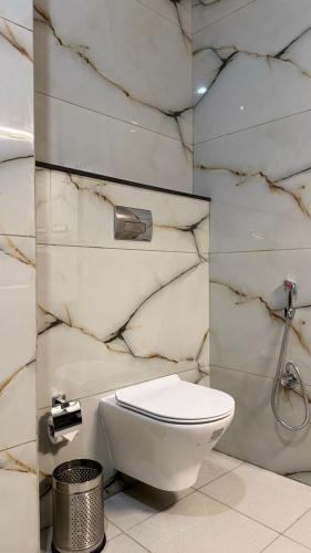 a bathroom with a toilet and a marble wall at Hotel Ivory Hills in Kotdwāra